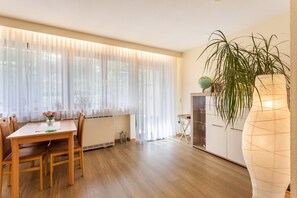 Un coin repas comprenant une table, des chaises, un vase avec des fleurs et une grande plante.