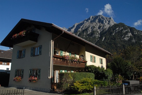 A two-story building with balconies, a mountain in the background, and a clear sky.