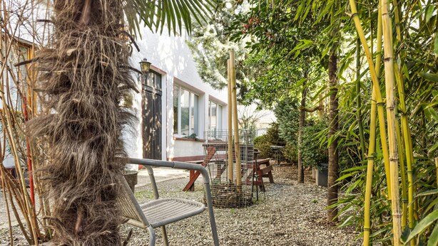Un patio con una silla, una mesa y una jaula para pájaros.