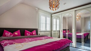 Un dormitorio con una cama grande, un armario con espejos y una lámpara en el techo.