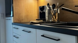 A modern kitchen with white cabinets, a wooden accent wall, and a coffee machine.