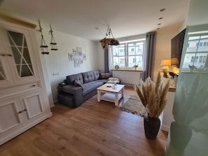 Ein Wohnzimmer mit grauem Sofa, einem weißen Couchtisch und einer Pendelleuchte.