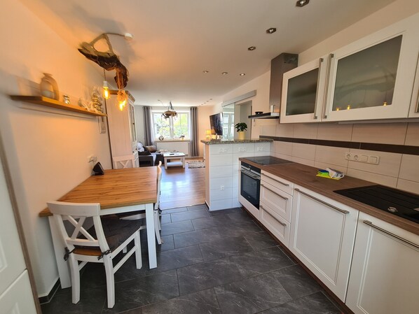 Eine moderne Küche mit weißen Schränken, einem Holzespeisetisch und einem eingebauten Backofen.
