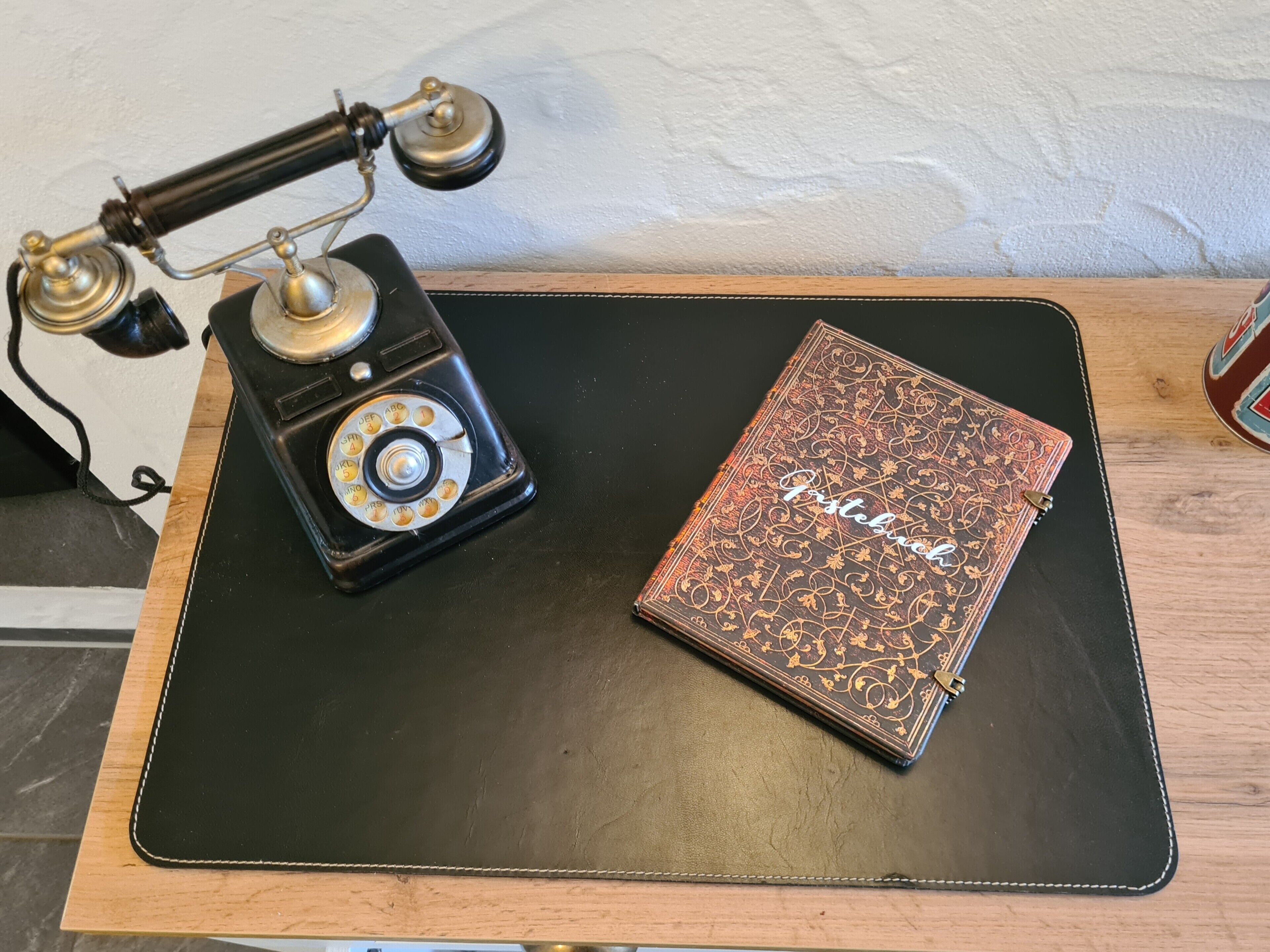 Un telefono a disco d'epoca e un quaderno con copertina in pelle su un tappetino nero.