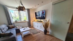 Una sala de estar moderna con sofá, mesa de centro, televisor y plantas decorativas.