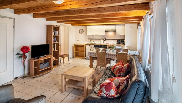 A living room with a sofa, a coffee table, a TV, and a bookshelf.