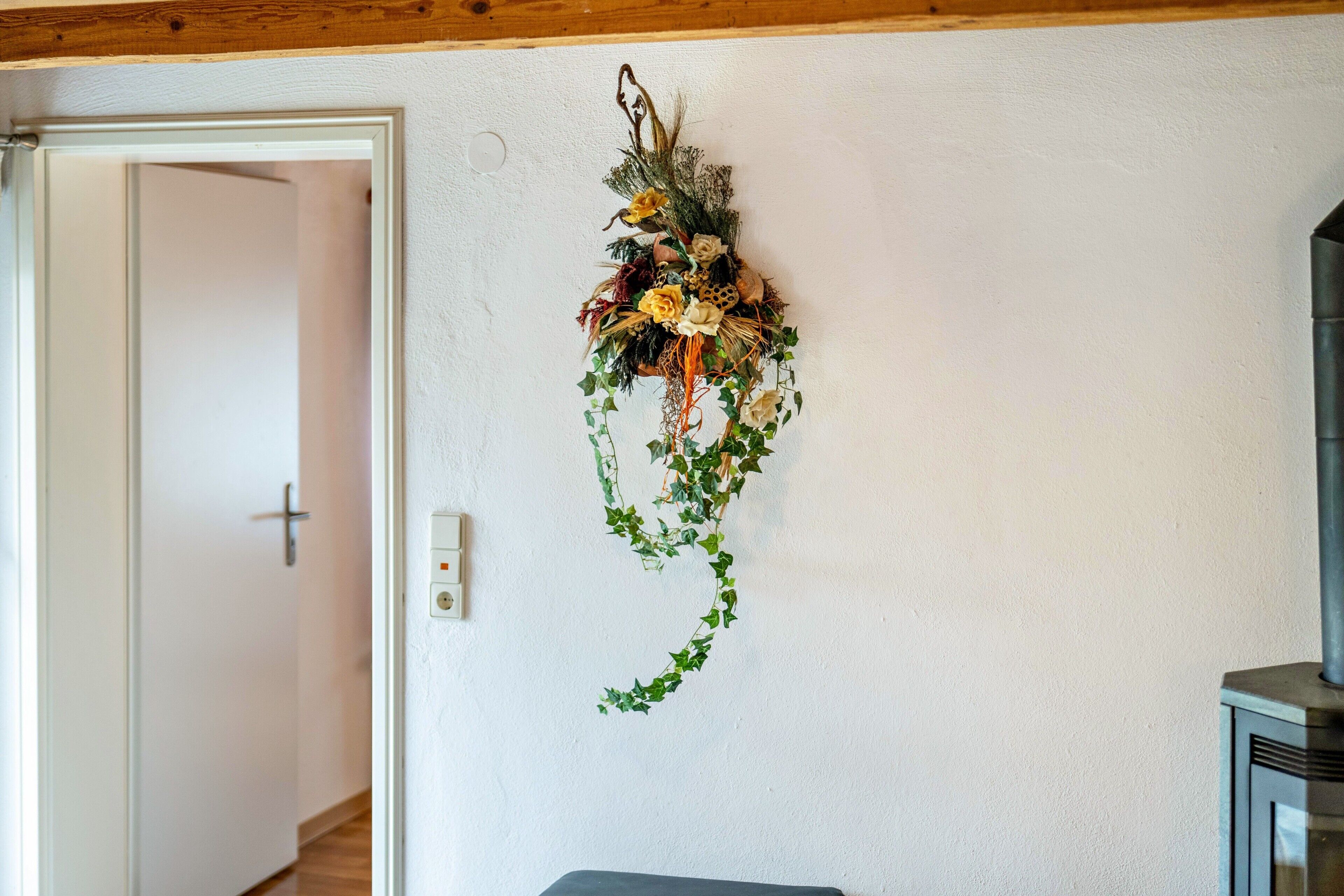 A room with a white wall, a door, a fireplace, and a wall-mounted decoration.