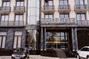 A hotel entrance with a grand facade, large glass windows, and a prominent "HOTEL" sign. - PGA Hotel (Tashkent)