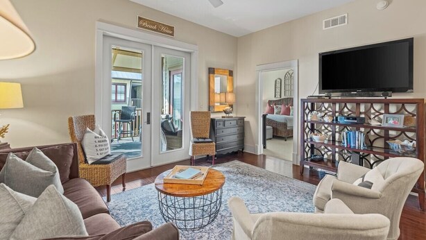 A living room with a sofa, armchairs, a coffee table, a TV, and a bookshelf. - Deeded Beach Access - 2 BR + Twin Bunks (Santa Rosa Beach)