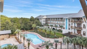 Et hotel med swimmingpool, flere balkoner og udsigt over det grønne omkringareal.