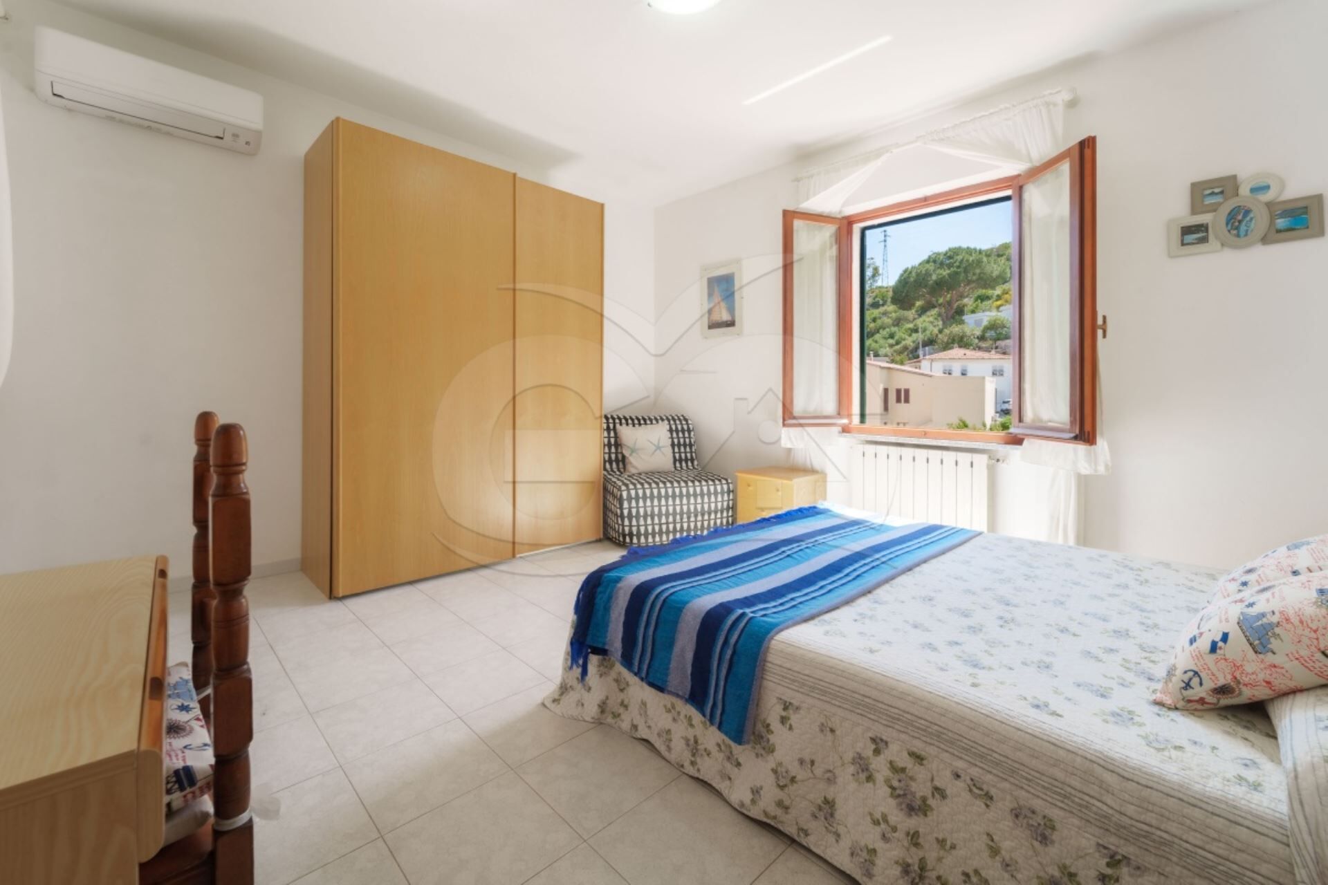 Une chambre à coucher avec un lit, une chaise, une armoire et une fenêtre donnant sur un beau paysage.