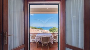 Ein Balkon mit Tisch und Stühlen mit Blick auf eine Küstenlandschaft.