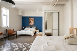 A hotel room with two beds, a large mirror, a blue accent wall, and a modern chandelier. - The Printhouse-Boutique Apt by SeaNRent  (Haifa)