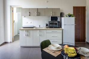 Une cuisine moderne avec des meubles blancs, un four à micro-ondes, une machine à café et un réfrigérateur.