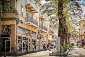 Une rue bordée de bâtiments, d’arbres et d’une enseigne.