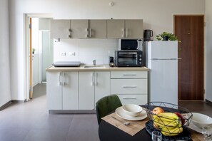 Une cuisine moderne avec des meubles blancs, un four à micro-ondes, une machine à café et un réfrigérateur.