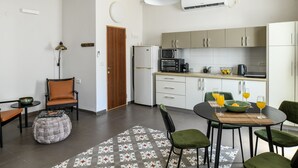 Una cocina moderna con refrigerador, microondas y tostadora. Hay una mesa de comedor con sillas y un tazón de fruta.