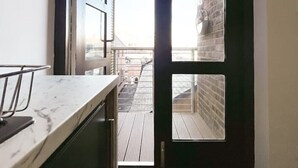 Ein schmaler Flur mit einer Marmorarbeitsplatte und einer Tür zu einem Balkon mit Blick auf Gebäude.