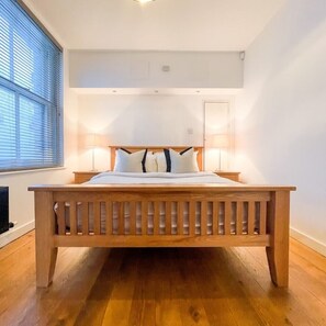 A bedroom with a wooden bed, white bedding, and two bedside lamps.
