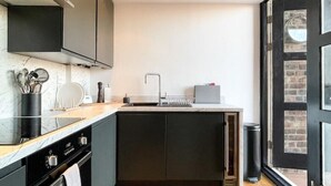Eine moderne Küche mit dunklen Schränken, einer Marmorarbeitsplatte und einem eingebauten Backofen.