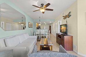 A living room with a sofa, a coffee table, a TV, and a ceiling fan. - Your Dream Getaway in Treasure Island. Heated Pool. Beachfront Tiki Bar. Hot Tub. On-site Cafe. (Treasure Island)
