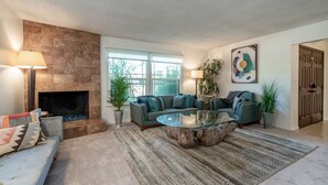 A living room with a fireplace, a sofa, a coffee table, and a large window.