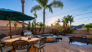 An outdoor patio with a stone fire pit, seating, and a small water feature.