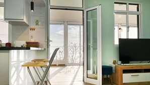 A modern kitchen with a dining area, a TV, and a balcony with a view. - Atlantic View, a Home in Madeira (Ponta do Sol)