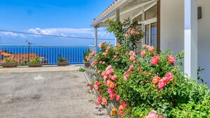 A building with a balcony overlooking a blue sky and a distant view of a coastline. - Atlantic View, a Home in Madeira (Ponta do Sol)