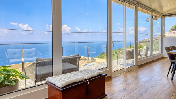 A room with a large sliding glass door leading to a balcony with a view of the sea. - Atlantic View, a Home in Madeira (Ponta do Sol)