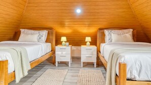 A cozy attic bedroom with two wooden beds, nightstands with lamps, and a sloped wooden ceiling. - Atlantic View, a Home in Madeira (Ponta do Sol)