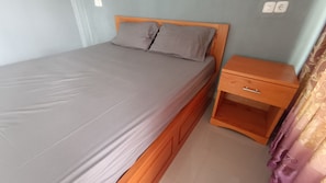 A single bed with a wooden headboard and a nightstand with a drawer. - OYO 93603 Nurbata Holdings (Mertak)