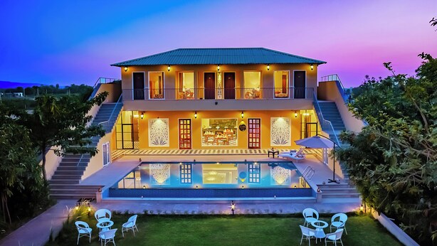 A two-story house with a swimming pool, outdoor seating, and a staircase leading to the upper floor. - Ananyamaya Nature Lodge (Sawai Madhopur)