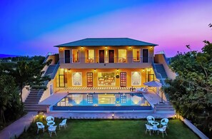A two-story house with a swimming pool, outdoor seating, and a staircase leading to the upper floor. - Ananyamaya Nature Lodge (Sawai Madhopur)