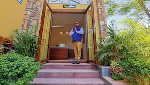 A man standing at the reception of a building with a stone facade and a sign above the entrance that reads "Reception." - Ananyamaya Nature Lodge (Sawai Madhopur)