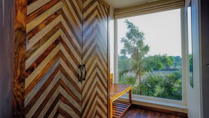 A room with a large window, a wooden chair, and a chevron-patterned wall. - Ananyamaya Nature Lodge (Sawai Madhopur)