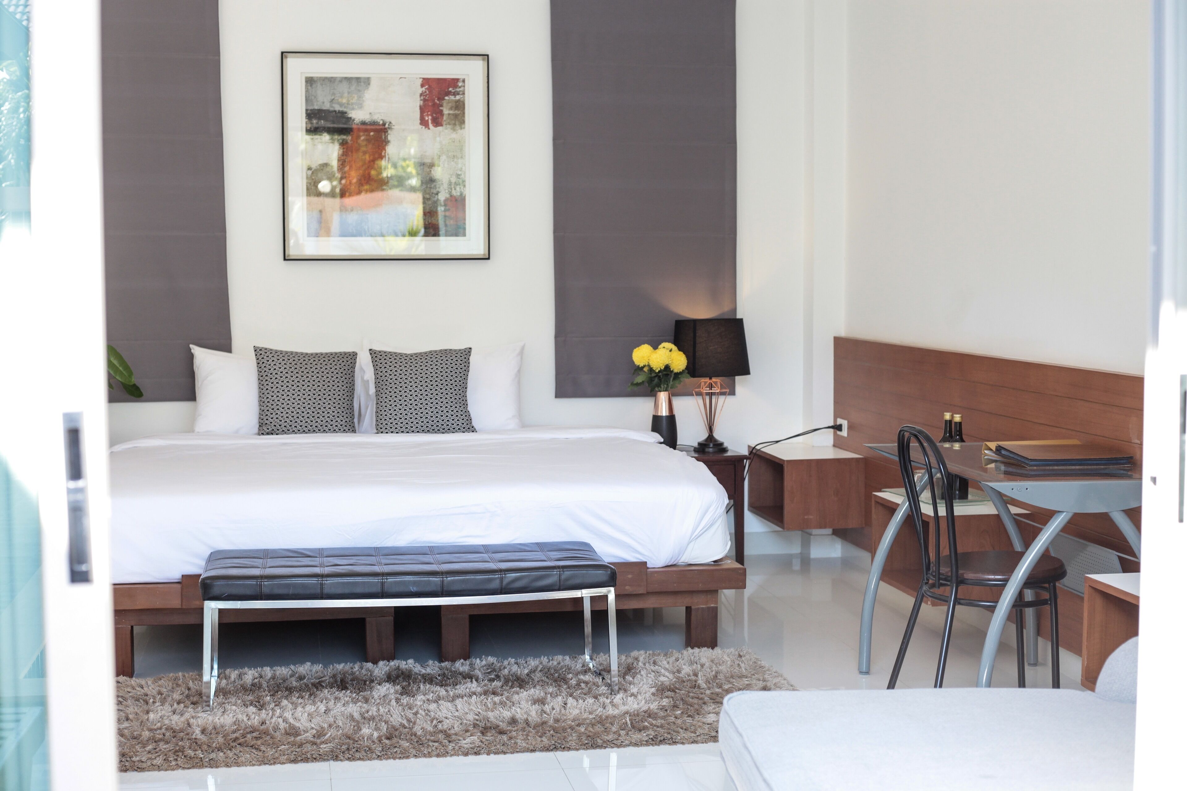 A modern bedroom with a large bed, a desk, and a chair.