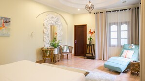 A bedroom with a bed, a chair, a desk, a mirror, and a window with curtains. - Phuket Cleanse (Rawai)