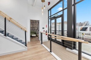 Ein modernes Interieur mit Treppe, Holzboden und großen Fenstern.