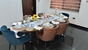 A dining table set with plates, glasses, and flowers, surrounded by chairs. - UrbaN RootZ  (Abuja)