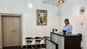 A reception area with a marble floor, a reception desk, and a painting on the wall. - UrbaN RootZ  (Abuja)