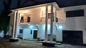 A two-story building with a covered entrance, columns, and a balcony. - UrbaN RootZ  (Abuja)