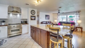 A kitchen with a central island, stainless steel appliances, and a dining area with a table and chairs. - Poolside Paradise! Central Merritt Island Home (Merritt Island)
