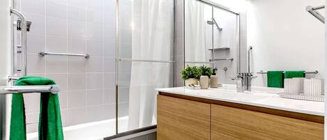 A modern bathroom with a glass shower enclosure, a wooden vanity, and a large mirror.