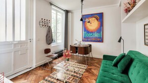 A living room with a green sofa, a coffee table, and a dining area with a table and chairs.
