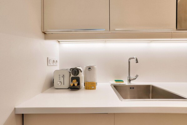 A modern kitchen with a stainless steel sink, a built-in oven, and a coffee maker.