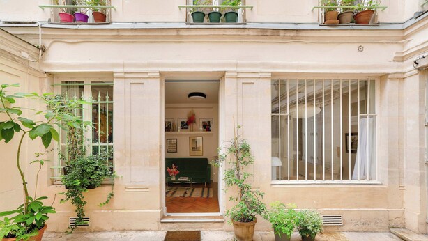 A building entrance with a door, potted plants, and a window with bars.