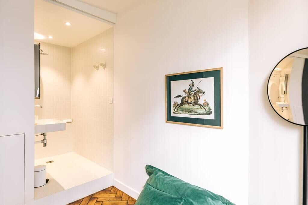 A bathroom with a white sink, a shower, and a framed picture on the wall.