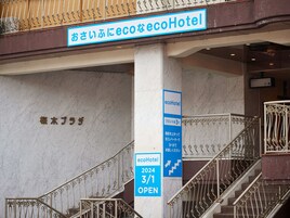 A hotel entrance with a sign indicating ecoHotel and a staircase with ornate metal railings.