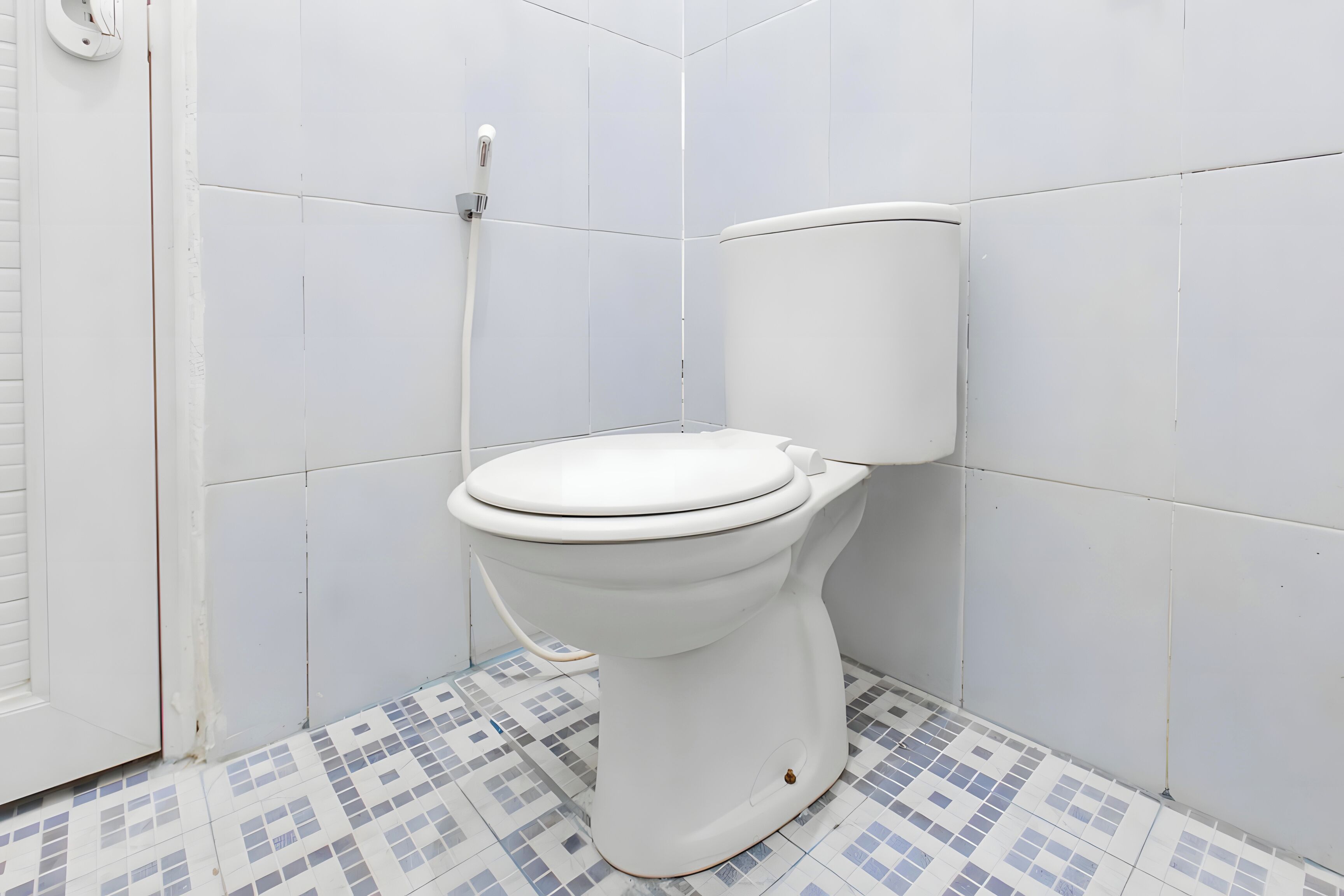 Eine weiße Toilette in einem Badezimmer mit gefliesten Wänden und Boden.